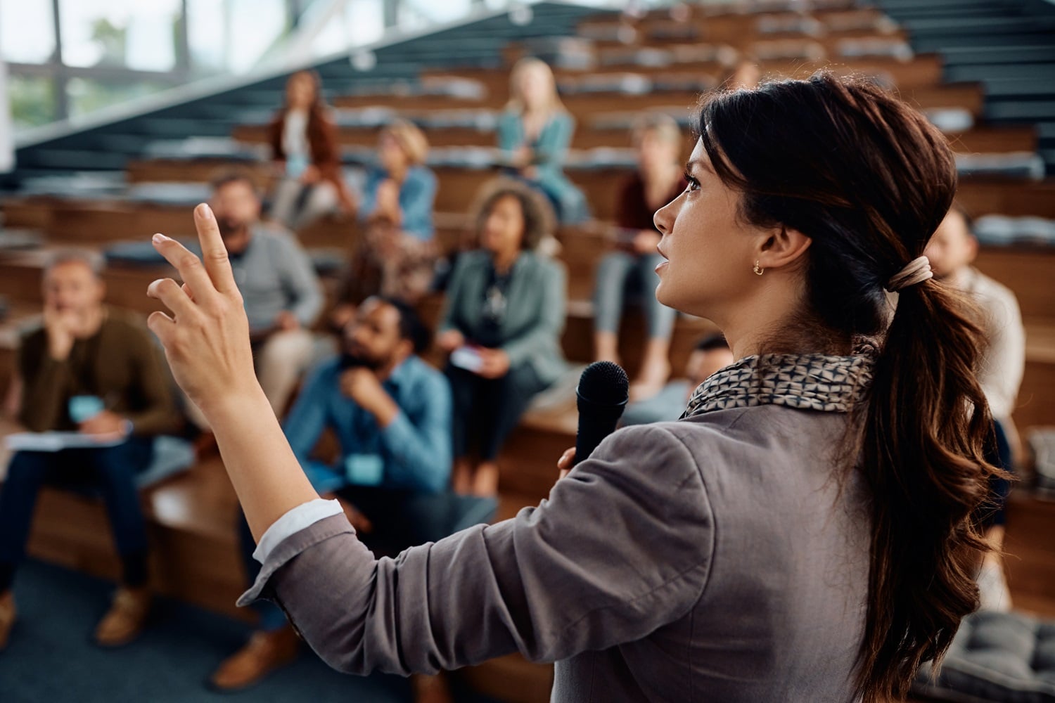 Female business leader talking to group of seminar attendees at convention center.