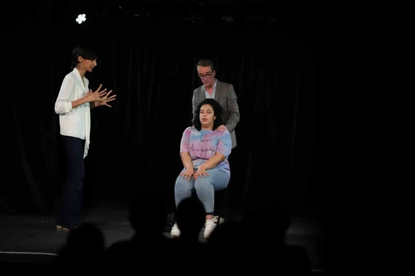 trois élèves en pleine représentation théâtrale sur une scène d'Avenue du Spectacle utilisant la confiance en soi enseignée lors des cours de théâtre pour jouer la comédie